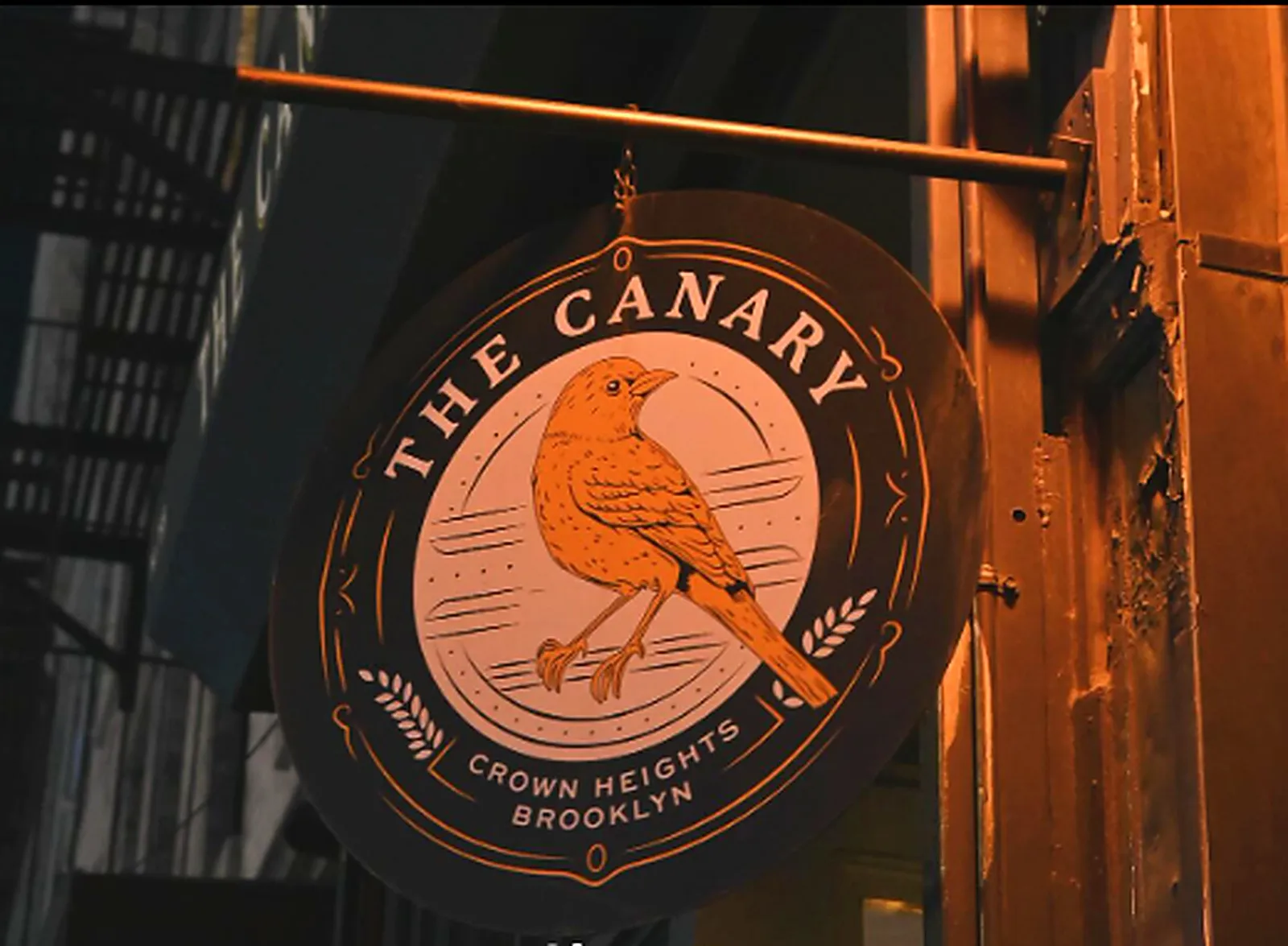 The Canary's hanging sign on Franklin Avenue: a gold canary on a black roundel, Crown Heights Brooklyn
