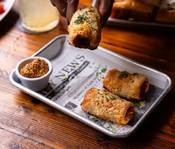House sausage rolls with wholegrain mustard, served on newsprint